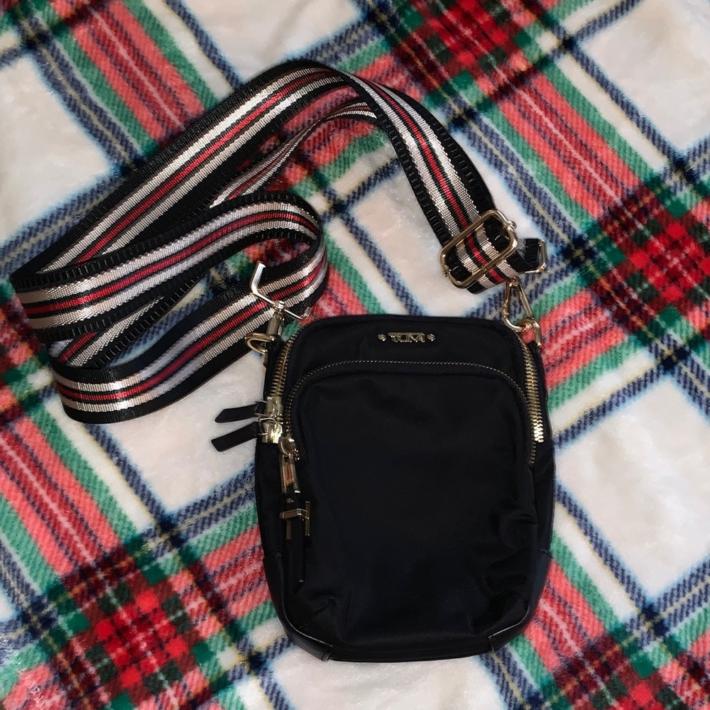 Tumi Crossbody bag in black nylon with an adjustable striped strap.
Very nice !
